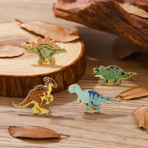 Lot de quatre broches dinosaures en émail coloré présentées sur des socles en bois