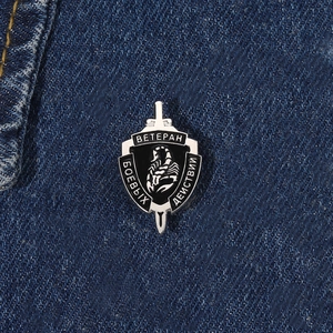Detail of shield-shaped metal scorpion veteran brooch on blue denim background