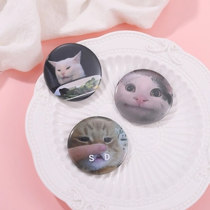 Three cute cat meme round badges featuring funny expressions in a white ceramic dish