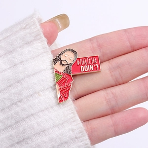 Detail of Whatcha Doin' religious character enamel pin on a white knitted sweater sleeve