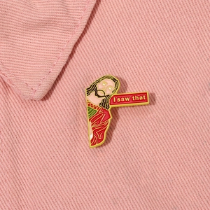 Jesus cartoon enamel pin with 'I saw that' text on pink denim fabric