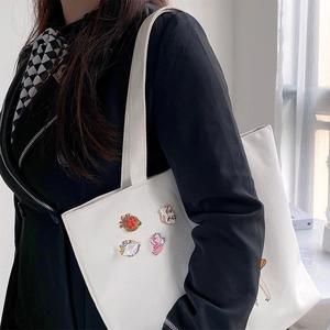 Artistic anatomical heart enamel pins set on a white canvas bag with colorful floral details