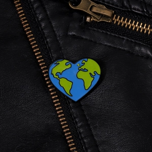 Spilla in smalto a forma di cuore con terra blu sul risvolto di una giacca di pelle