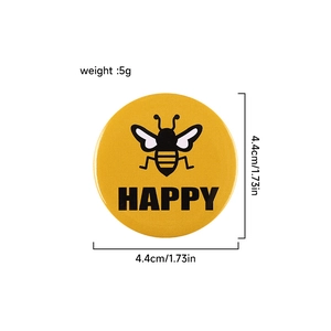 Yellow tinplate round pin badge featuring a black bee and Happy text, 4.4cm diameter