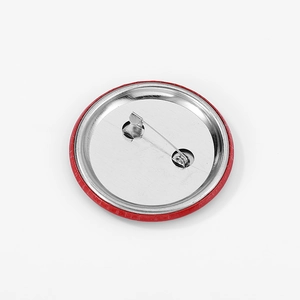 Round tinplate badge with secure silver metal safety pin and red edges on white background