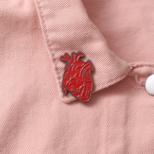 Anatomical red heart enamel brooch with medical labels on a pink denim jacket collar