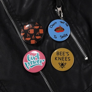 Detail of four colorful tinplate badges pinned on a black leather jacket for decoration