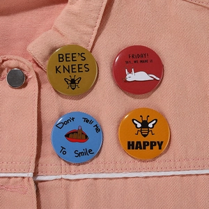 Close-up of set of 4 cartoon tinplate badges pinned on a pink denim jacket