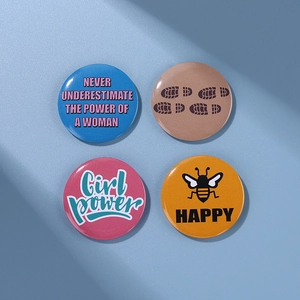 Set of four round tinplate lapel pins with inspirational text and creative graphics