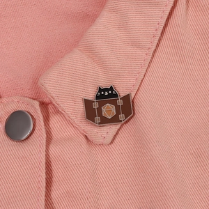 Cute black cat enamel pin with d20 dice on brown screen pinned to pink fabric