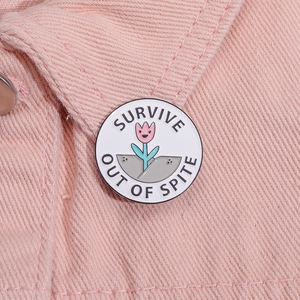 Makrodetail der runden Emaille-Tulpenbrosche mit SURVIVE OUT OF SPITE Text auf Denim