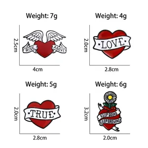 Variety of enamel heart pins with wings and quotes like LOVE and RISE ABOVE on white background