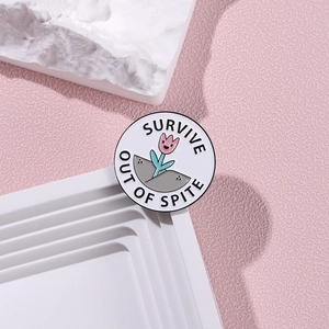 Minimalist round enamel flower pin with Survive Out Of Spite text on pink background