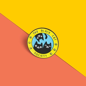 Detail of a round Black Cat Society enamel pin badge with vibrant yellow and blue colors