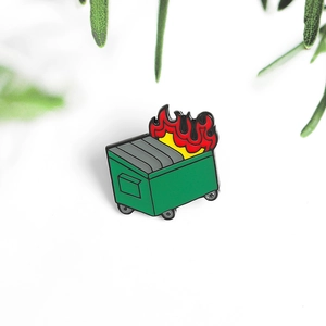 Kreative grüne Emaille-Nadel in Müllcontainer-Brand-Optik auf weißem Hintergrund