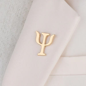 Close-up of golden Psi Greek letter brooch pinned on a beige blazer lapel
