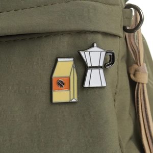 Détail des épinglettes en émail sac à café et cafetière moka sur un sac en toile