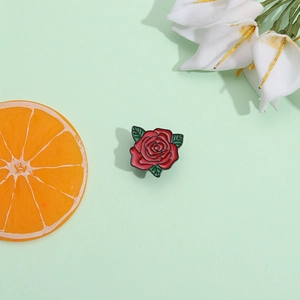 Squisita spilla smaltata a rosa rossa con foglie verdi su uno sfondo decorativo