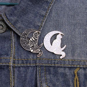 Punk style cat and moon enamel brooch set on blue denim jacket collar accessory