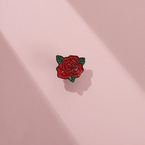 Spilla in smalto a forma di rosa rossa con foglie verdi su sfondo rosa