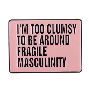 Pink enamel pin badge with 'I'M TOO CLUMSY TO BE AROUND FRAGILE MASCULINITY' slogan text