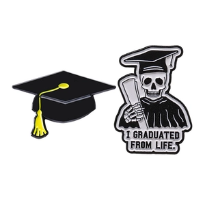 Graduation enamel pin set featuring a black doctoral cap and a skeleton with diploma