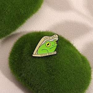Cute green frog in toast enamel pin badge with Let's Get This Bread slogan lettering