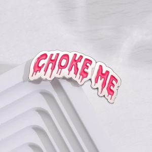 Macro shot of pink enamel 'CHOKE ME' letter brooch on white geometric stairs