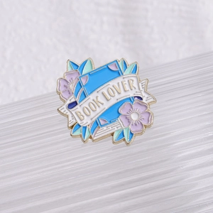 Detailed macro view of the Book Lover enamel pin with purple flowers and blue leaves