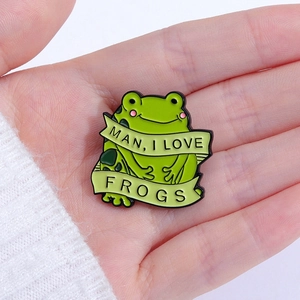 Cartoon green frog enamel pin featuring the slogan MAN I LOVE FROGS in a hand-held close-up