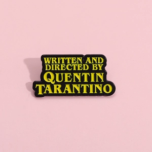 Épinglette en émail Quentin Tarantino avec texte jaune sur fond rose pastel