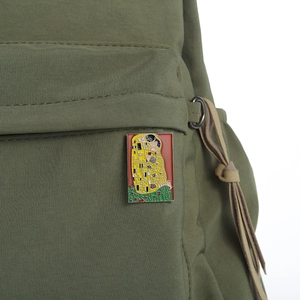 Artistic enamel brooch featuring The Kiss painting on olive green canvas bag strap