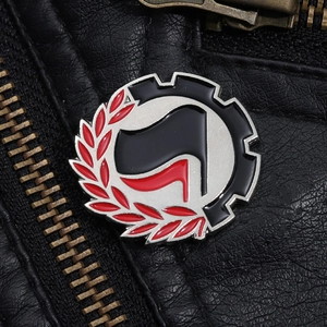 Detail of round metal enamel pin with crossed flags on a black leather jacket texture