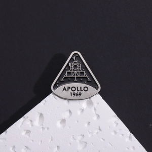 Black Apollo 1969 moon landing memorial enamel pin with lunar module on moon rock base