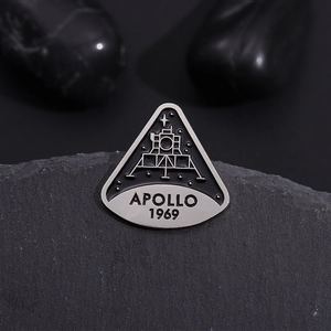 Apollo 1969 moon landing anniversary enamel pin badge on a dark textured rock