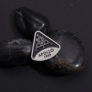 Detailed view of Apollo 1969 moon landing enamel pin on black aesthetic background