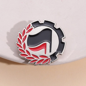 Round geometric metal enamel badge with gear and laurel leaf design on a pin