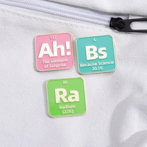 Three colorful enamel chemistry pins on canvas bag featuring periodic element designs