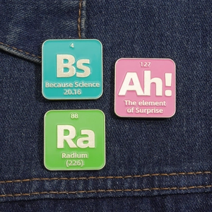 Detailed view of colorful chemical element enamel pins on blue denim fabric background