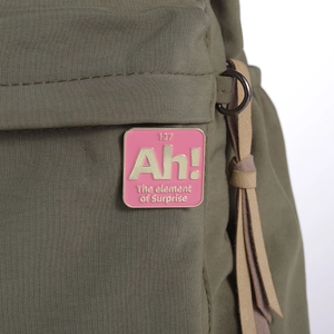 Detail of pink enamel badge with gold text on green fabric with leather tassel