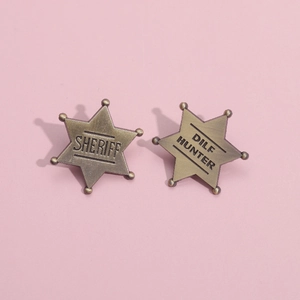 Set of two vintage bronze hexagonal sheriff star metal badges on a pink background