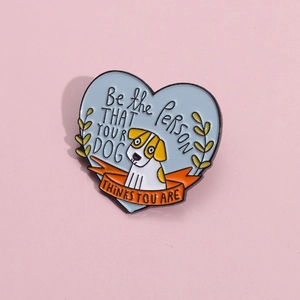 Cartoon dog enamel pin with motivational quote on blue heart background over pink base
