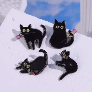 Détail de quatre épingles en émail chat noir avec roses rouges sur pierre blanche