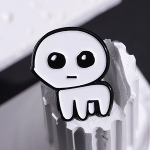 Macro view of white TBH Creature enamel pin placed on a white decorative pillar