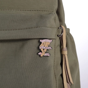 Gros plan d'un pin's émaillé Mysterious Leg Bruise Club sur un sac à dos en nylon