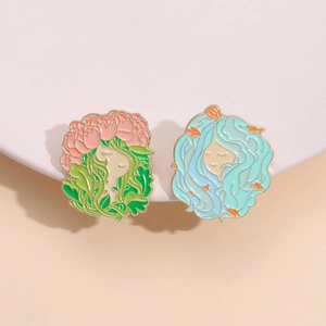 Artistic enamel brooches featuring flower and ocean girl designs on a white round stand