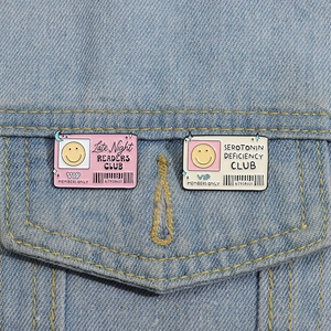 Macro shot of creative pink and white VIP card enamel pins attached to denim jacket pockets