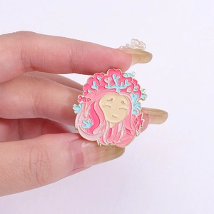 Cartoon mermaid enamel brooch with pink hair and coral details in golden metal finish
