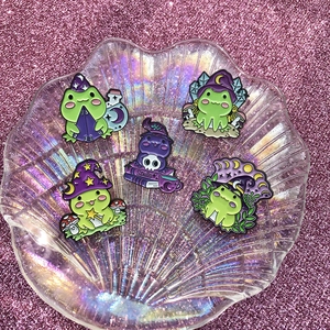 Wizard frog enamel pins set with purple magic hats on shimmering background