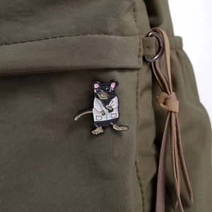 Detail of a mouse scientist brooch in white coat on a green nylon bag strap